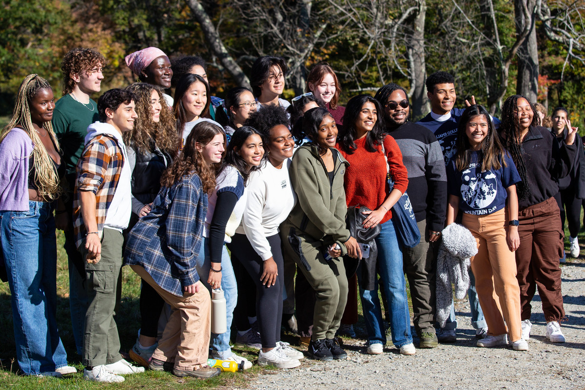 A diverse group of students poses for a group photo while taking a hike on Mountain Day in October.