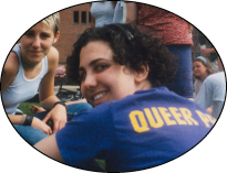 Queer Pride Week, 1990's: color photograph of former Williams student smiling. They are wearing a purple shirt and across from them is an individual in a white sleeveless shirt, also smiling.